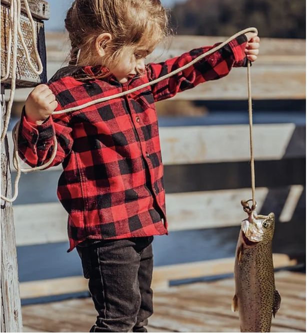Young angler on the dock holding a freshly caught trout